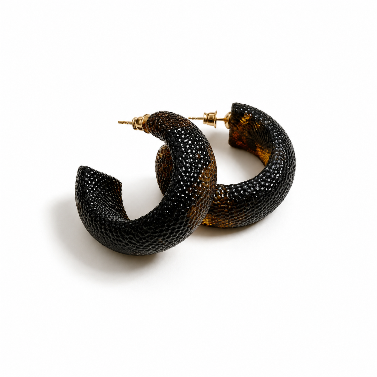 A pair of baltic amber, textured black hoop earrings with gold post backings, displayed on a clean white background. — Baltijos gintaro papuošalai, rankų darbas Lietuvoje